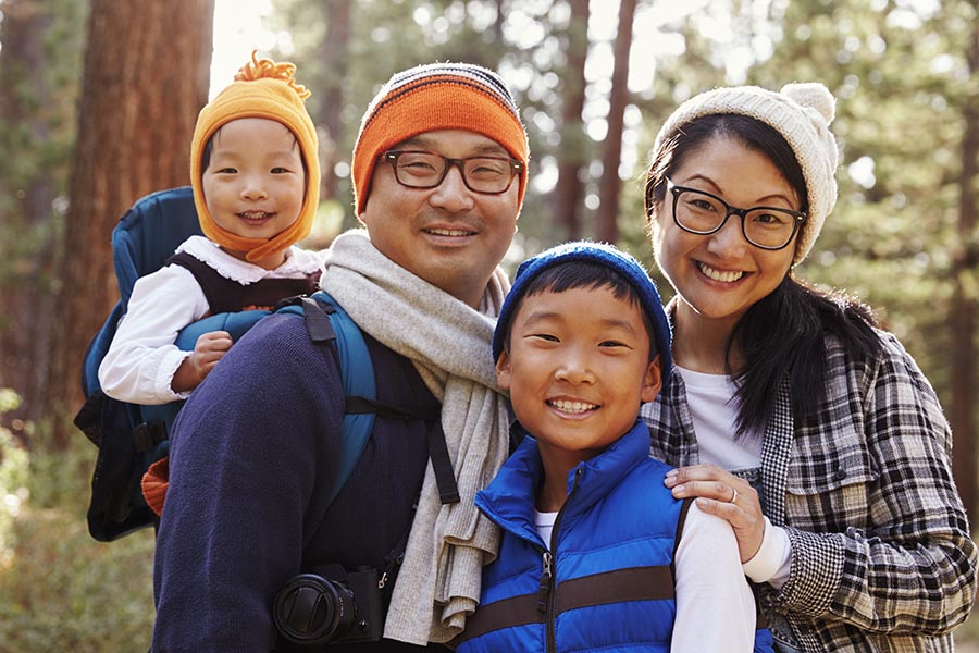 Personal Insurance - Father, Mother, Young Son, and Toddler Daughter on a Hike in the Fall Among Pine Trees, Daughter in a Hiking Backpack